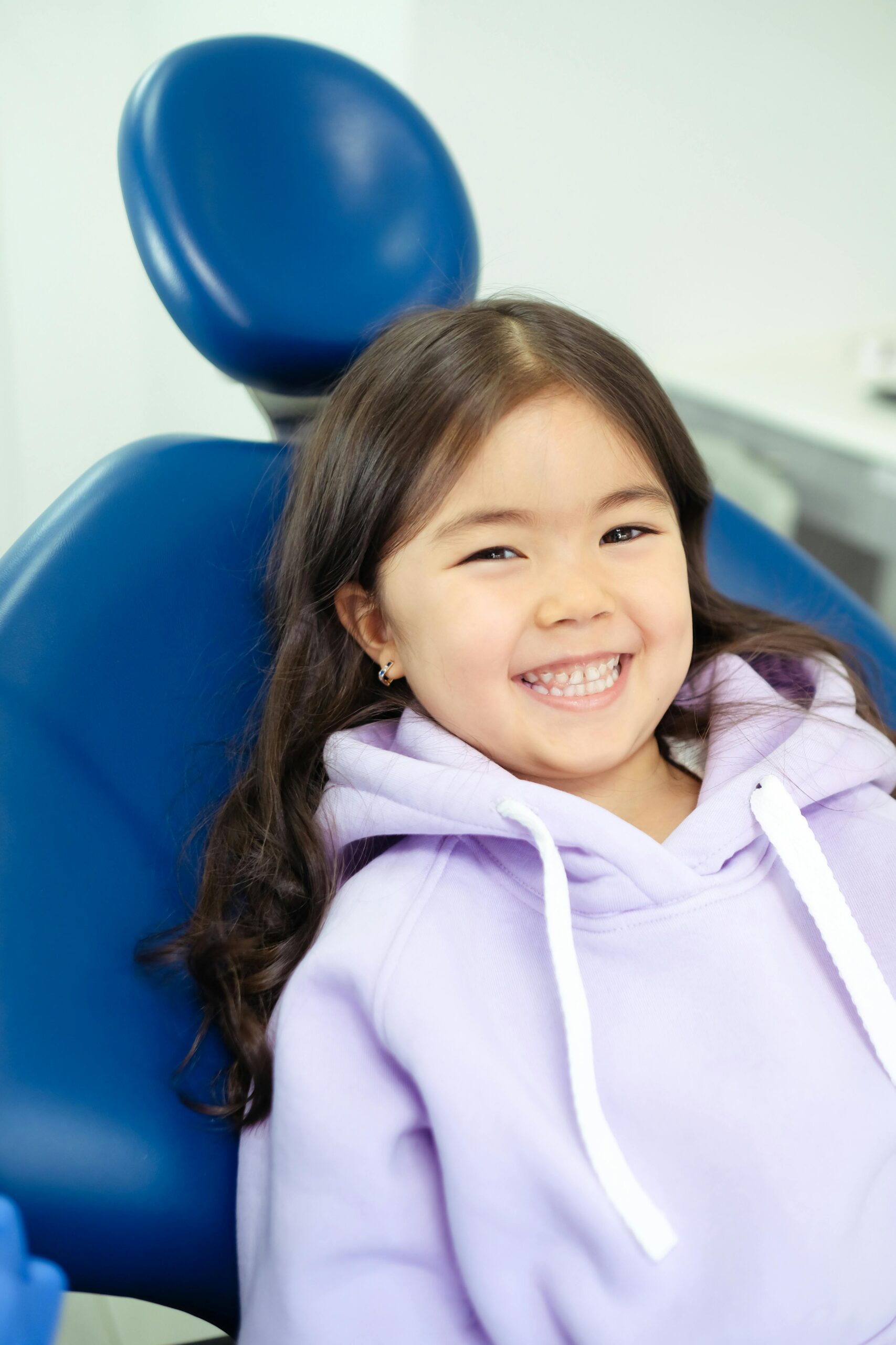 Joyful young girl with a radiant smile sitting comfortably in a dental chair.