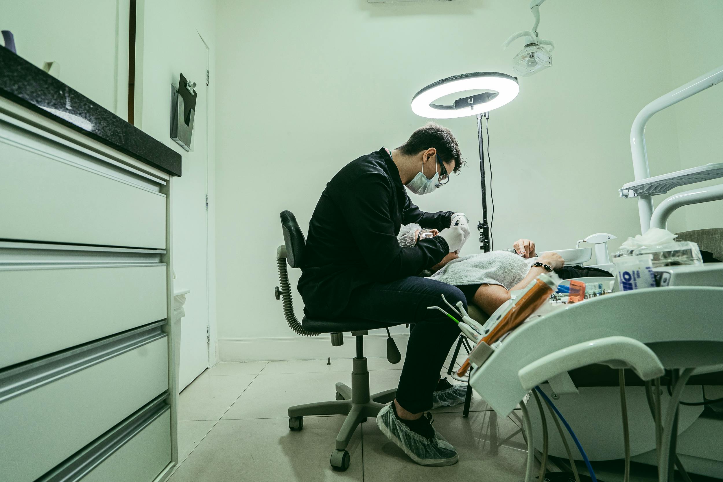 A dentist wearing a mask treats a patient in a modern dental clinic in Brazil.