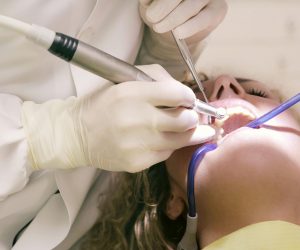 Close-up of a dental procedure with tools in a clinic setting, patient undergoing treatment.