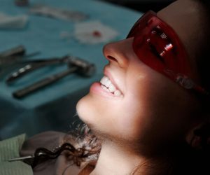 pexels-photo-4269691-4269691 Close-up of a woman smiling with protective glasses at a dental clinic, highlighting her teeth.