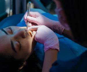 Emergency Dentist examines patient during a dental procedure with precision tools.