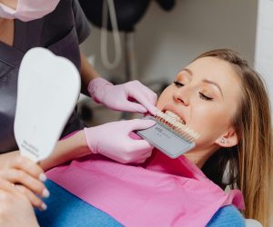 Cosmetic Dentistry Dentist using a shade guide to match tooth color for a patient in a dental clinic.