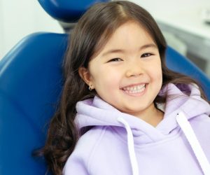 Joyful young girl with a radiant smile sitting comfortably in a dental chair.